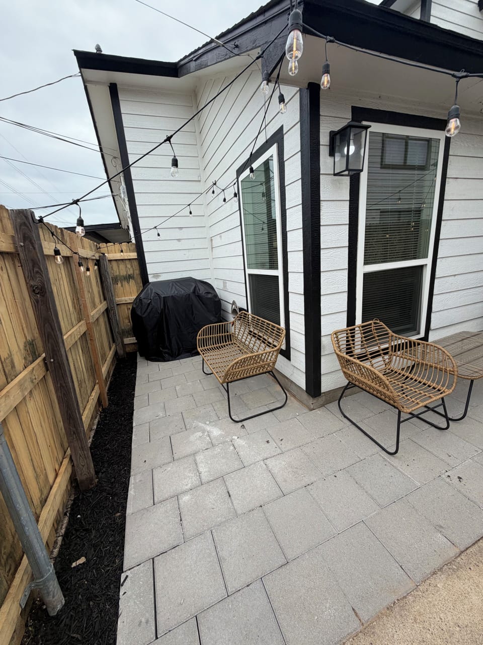 Private patio with string lights, lounge seating, and outdoor grill