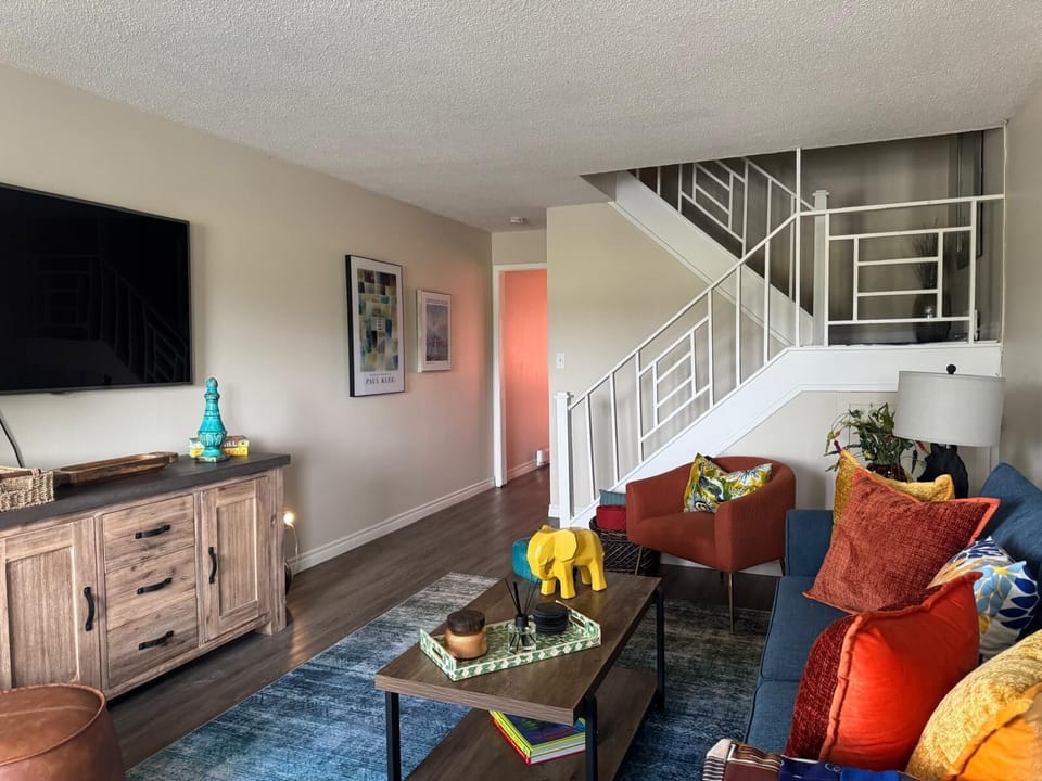 Bright, colorful living room with modern decor and a stylish staircase