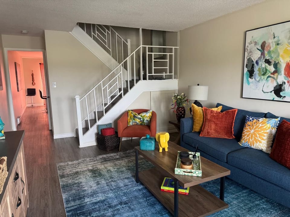 Bright, stylish living room with colorful decor and open staircase