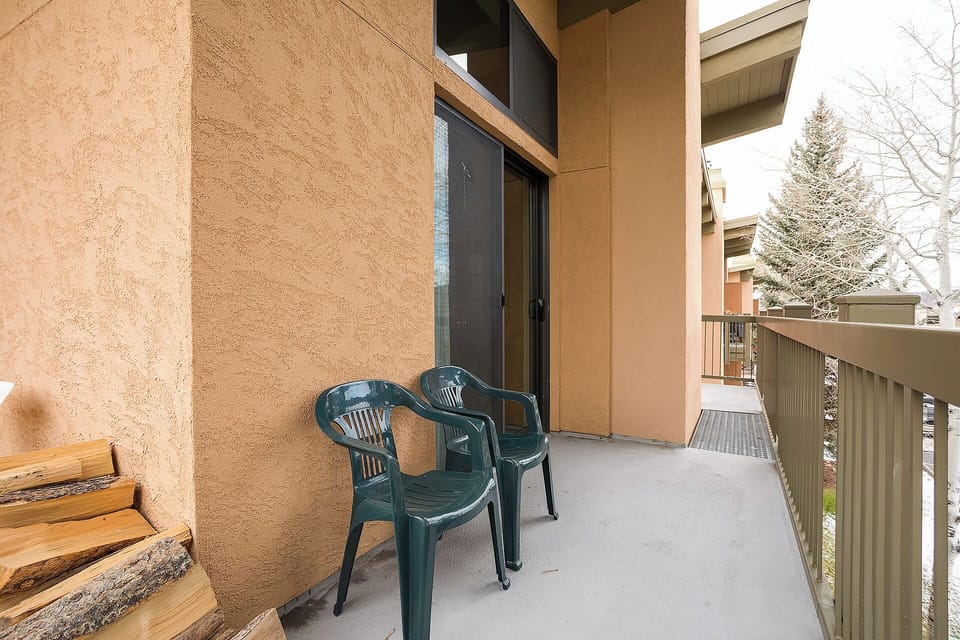 A private balcony awaits with seating for two, framed by mountain-area tranquility and seasonal evergreens—perfect for morning coffee or evening relaxation.