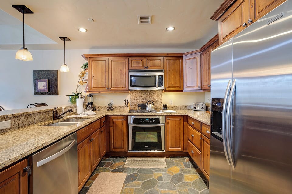 Your fully-equipped kitchen features granite counters, stainless appliances, and warm wood cabinetry—perfect for preparing meals or morning coffee in comfort.