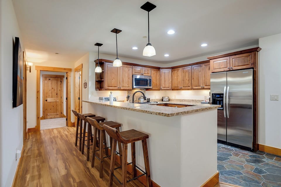 Your fully-equipped kitchen features warm wood cabinetry, granite countertops, stainless appliances, and a breakfast bar perfect for morning coffee or casual meals.
