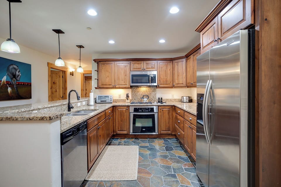 You'll love preparing meals in this fully equipped kitchen with granite counters, stainless appliances, and warm wood cabinetry, all bathed in natural light.