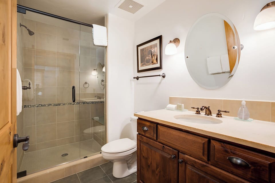Your private bathroom features a walk-in shower, warm wooden vanity, and southwestern charm—fresh, clean, and ready for your relaxation.