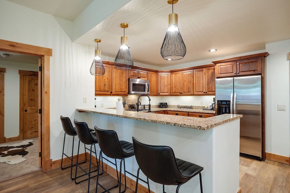 Gather around your spacious granite island with bar seating for five, where modern pendant lights illuminate your fully equipped kitchen with stainless appliances and warm wood cabinetry.