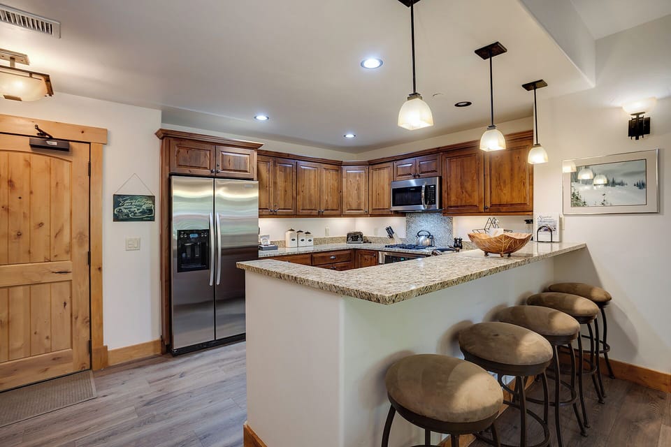 Gather around your granite breakfast bar with seating for four, where warm wood cabinetry and stainless appliances make meal prep a breeze in this welcoming open kitchen.