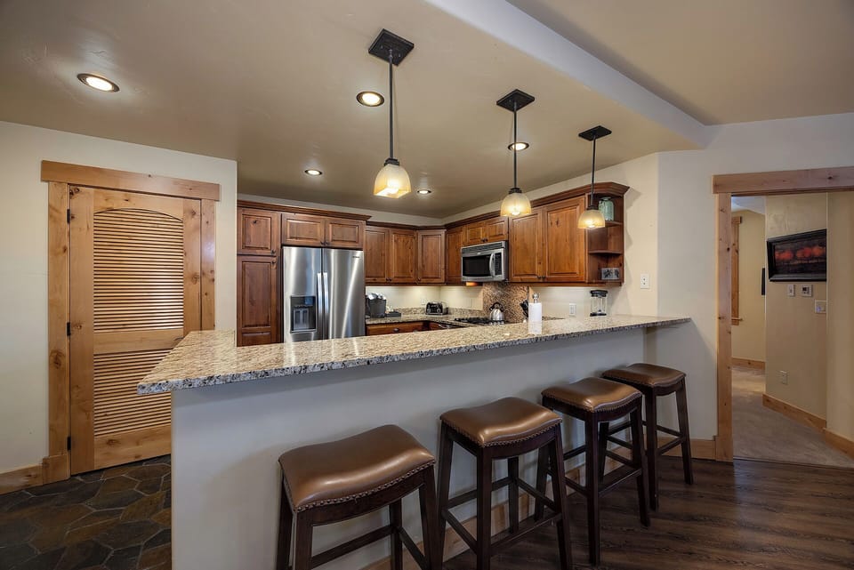 Gather around this welcoming kitchen with warm wood cabinetry, granite counters, and comfy bar seating—perfect for your morning coffee or evening conversations.
