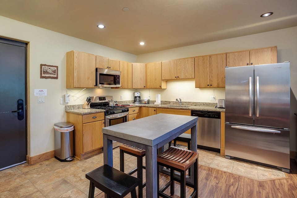 Your fully equipped kitchen features modern stainless-steel appliances, ample counter space, and a convenient island with seating—perfect for preparing meals or enjoying morning coffee together.