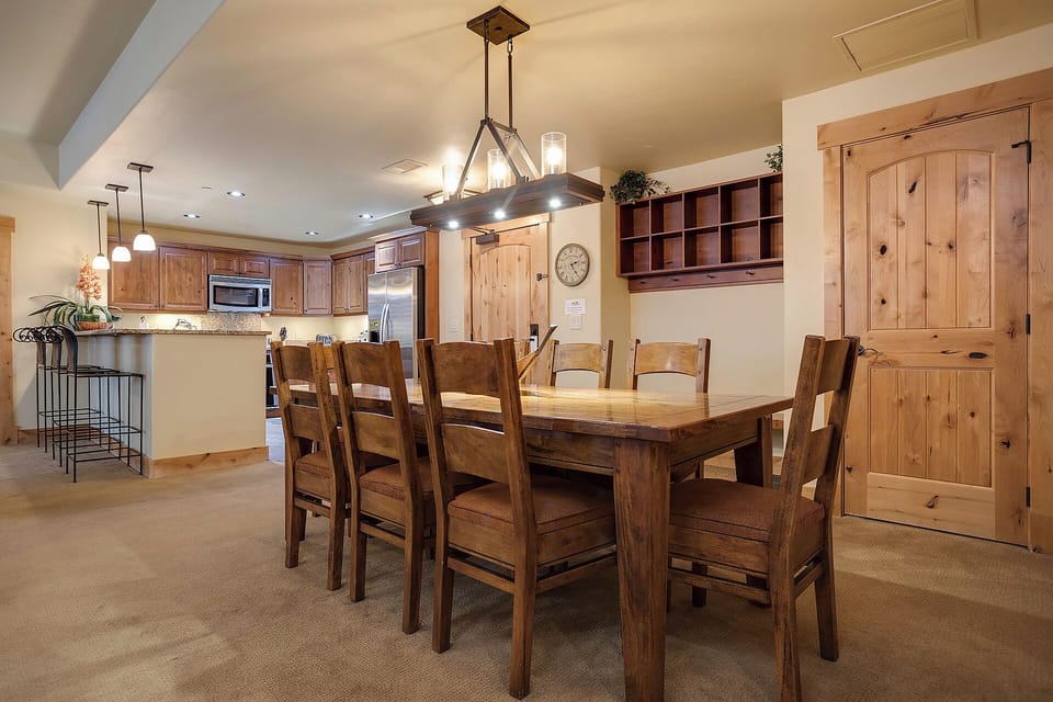 Gather your group around this spacious dining table, where rustic wood tones and modern kitchen amenities create the perfect setting for shared meals and memorable conversations.