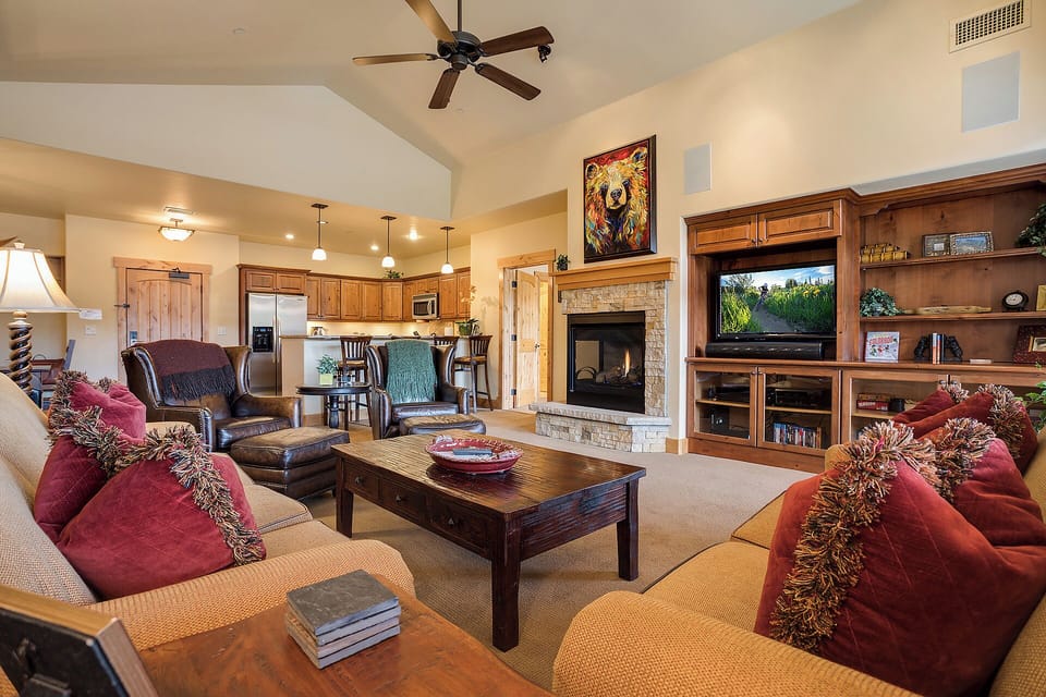 Sink into plush seating before a glowing stone fireplace while mountain scenery fills the flatscreen. This open-concept great room flows into a fully-equipped kitchen, inviting you to gather, relax, and feel at home.
