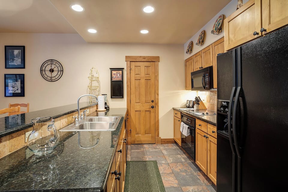 Cook your favorite meals in this inviting kitchen, featuring granite counters, warm wood cabinetry, full-size appliances, and thoughtful lighting—perfect for mountain getaways.