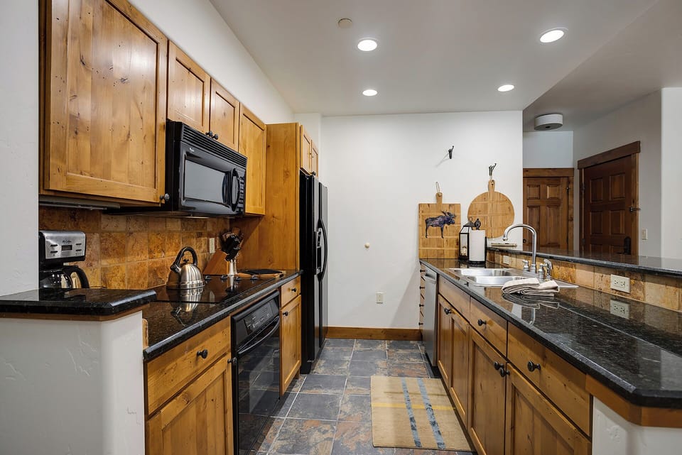 Your well-equipped kitchen with warm wood cabinetry, granite counters, and modern appliances invites you to cook your favorite meals or brew morning coffee in comfort.