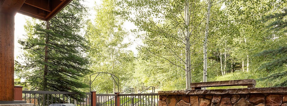 A spacious patio invites you to gather around the stone fireplace, surrounded by natural greenery and mountain tranquility, perfect for relaxing under the open sky.