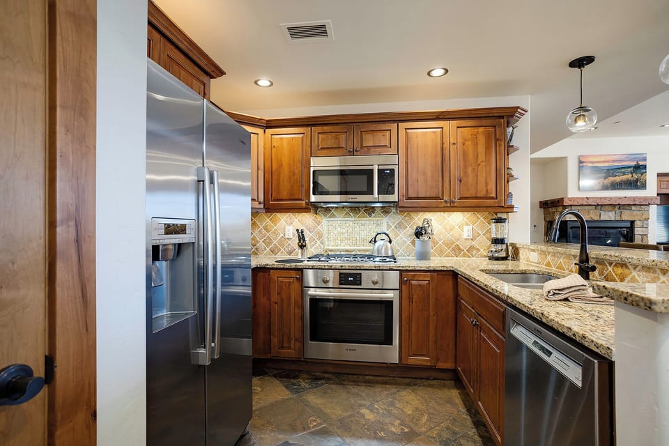Your gourmet kitchen awaits with gleaming stainless appliances, granite counters, and warm wood cabinetry—perfect for whipping up home-cooked meals or morning coffee.