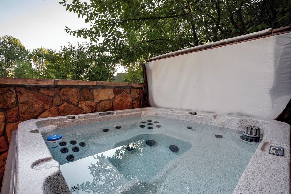 Soak away your cares in your private hot tub, nestled beneath the trees with warm stone walls framing your peaceful outdoor retreat.
