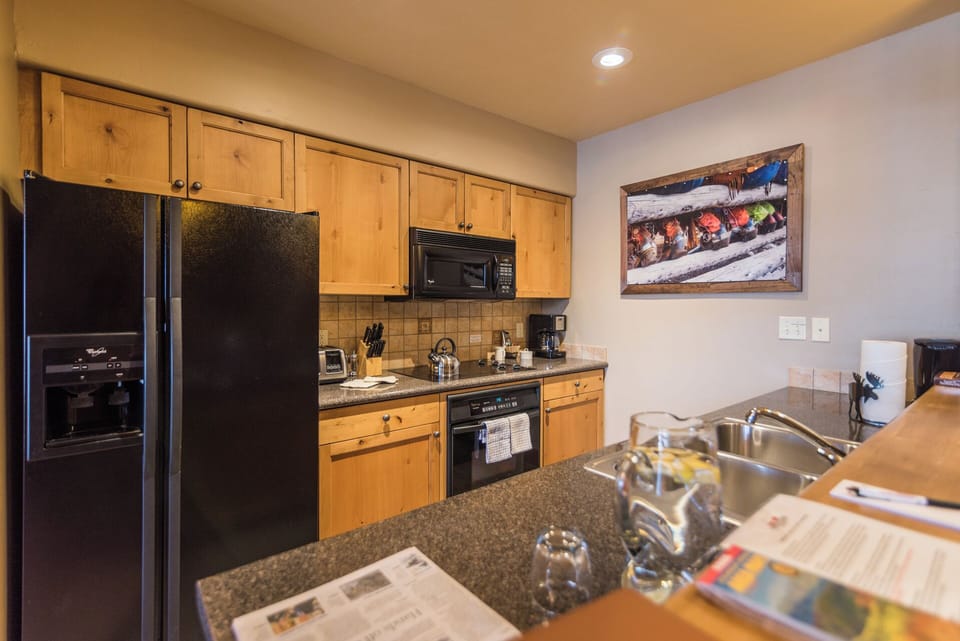 Your fully equipped kitchen features modern appliances, granite countertops, and warm wood cabinetry, ready for preparing homemade meals during your mountain getaway.
