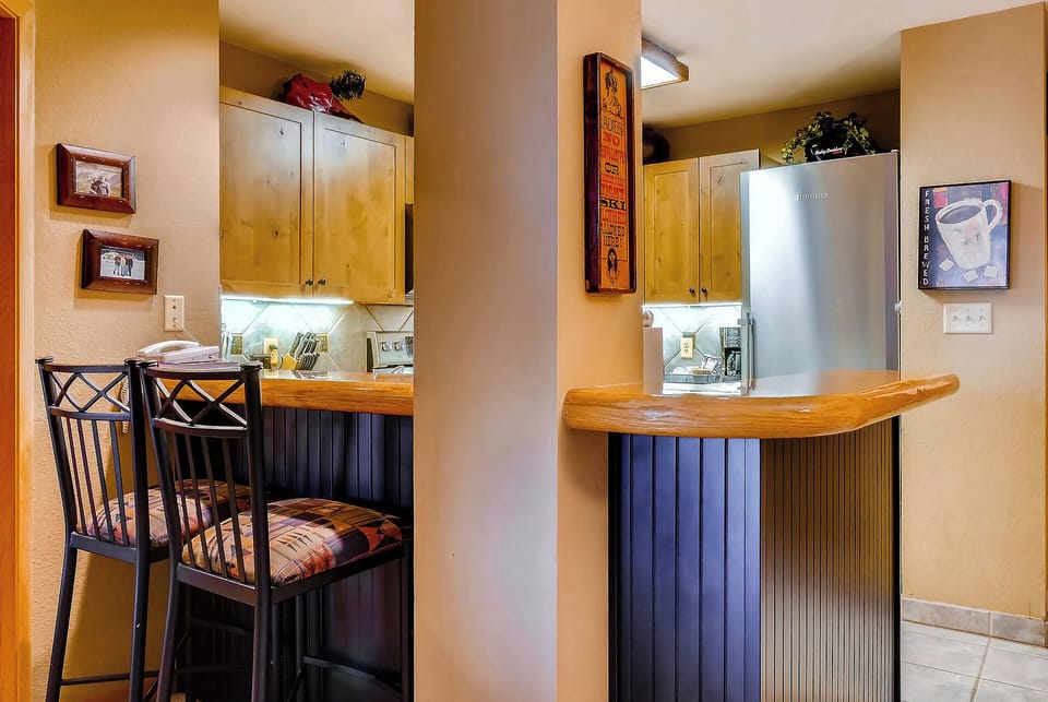 Enjoy your morning coffee at the breakfast bar, with a fully equipped kitchenette at your fingertips. The cozy seating and warm lighting create a welcoming space for meals and conversation.