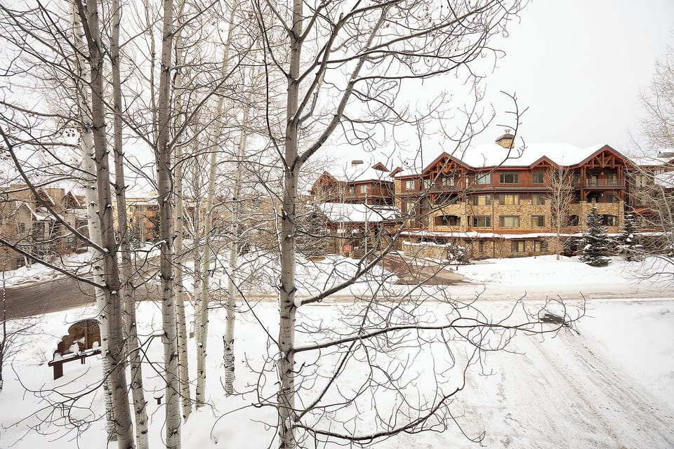 A snow-covered mountain lodge nestled among frosted aspens, with ski-in access and cozy alpine architecture creating the perfect winter retreat.