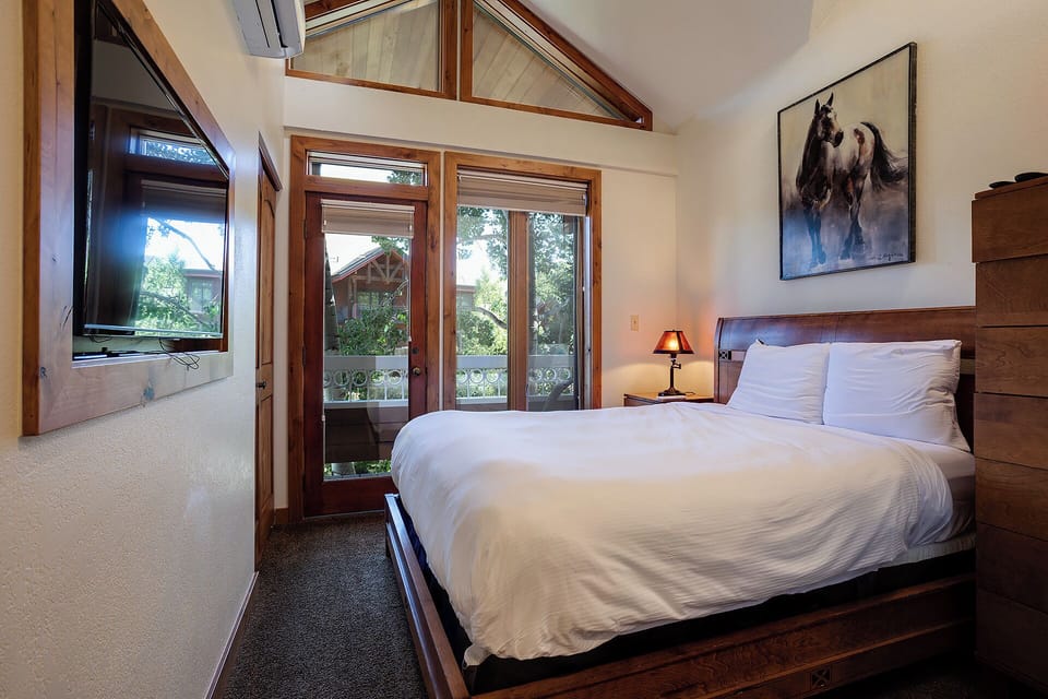 Your serene retreat features vaulted ceilings, a plush bed with crisp linens, private balcony access, and warm wood accents that invite you to unwind in comfort.