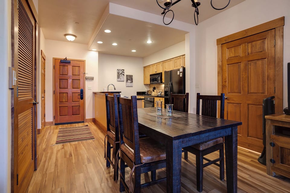 Step into your welcoming open-concept space where warm wood tones and rustic details set the tone. The dining area flows seamlessly into a fully equipped kitchen, ready for shared meals and cozy evenings.