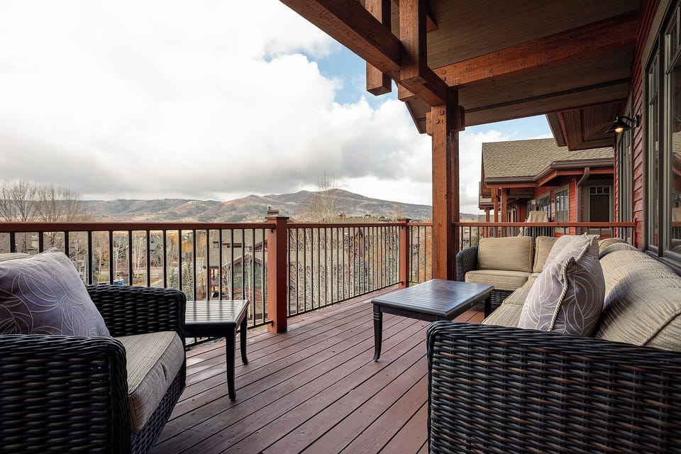 Expansive mountain views frame your private deck—perfect for morning coffee or evening relaxation in comfortable seating surrounded by stunning alpine scenery.