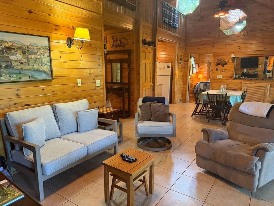Spacious Cabin Living Room — Wood interiors, comfortable seating, and a dining area overlooking the living space.