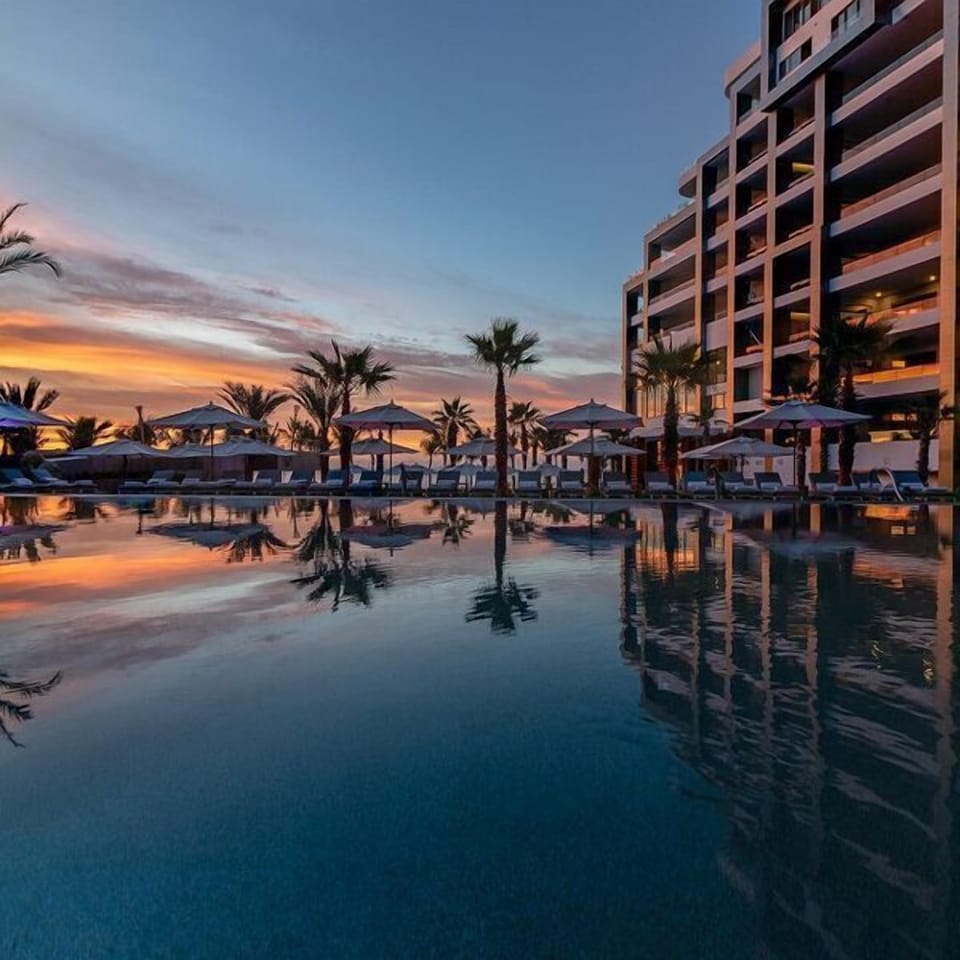 Resort-style sunset pool with palm views and modern luxury ambiance