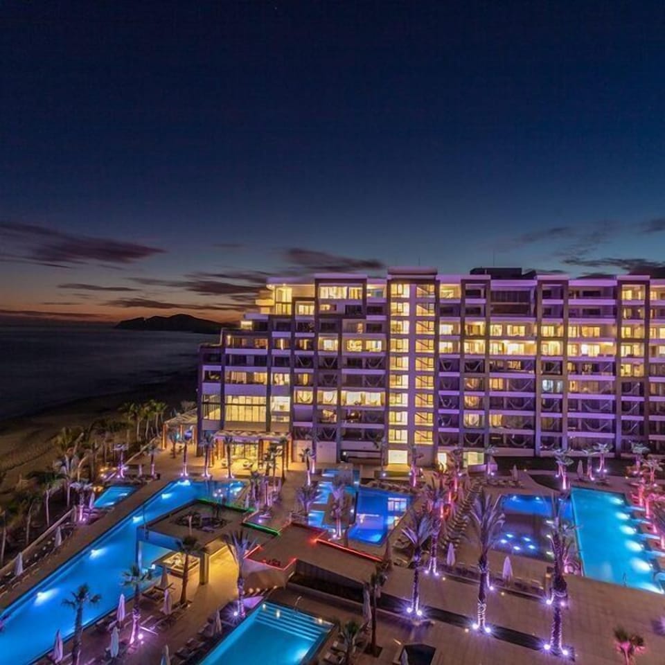 Beachfront resort at dusk with glowing pools and stunning oceanfront views