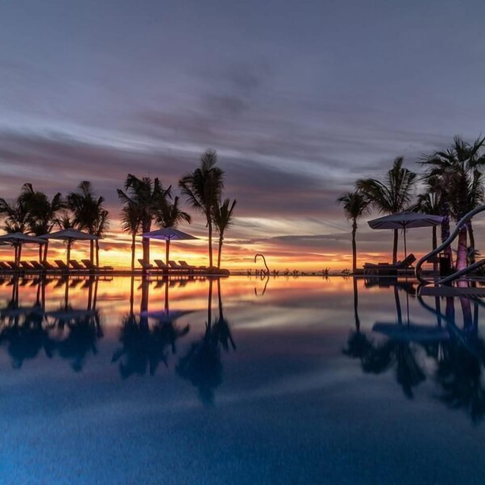 Sunset infinity pool with palms, loungers, and tranquil resort vibes