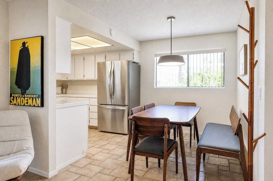 Gather around the dining table in your bright, modern kitchen—perfect for morning coffee or evening meals with loved ones, with sunlight pouring through the window.