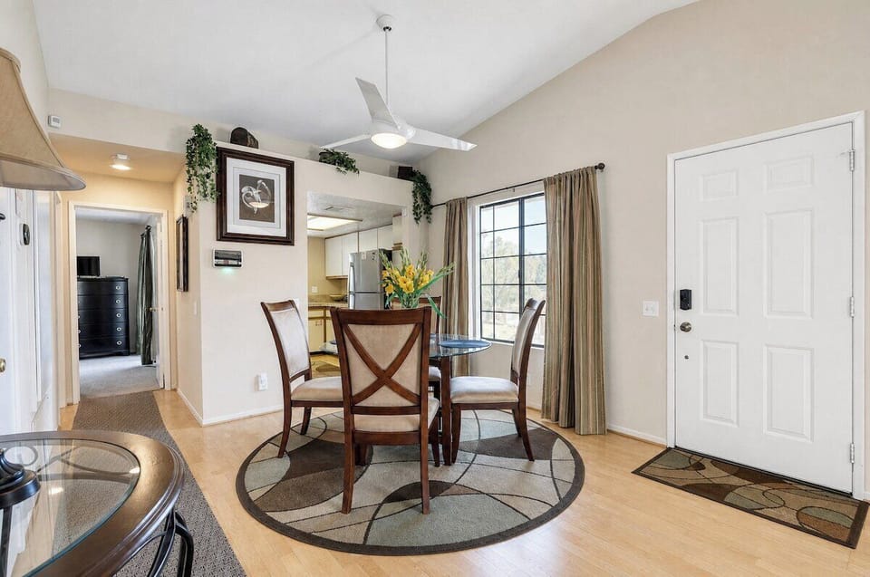 Gather around this inviting dining table, where natural light streams through large windows and a modern ceiling fan keeps you comfortable during meals together.