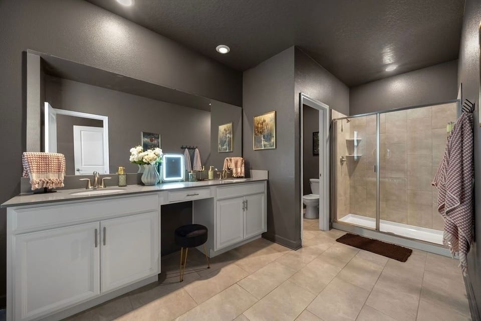 Features a vanity area, double sinks, hair dryer, walk-in shower and soaking tub