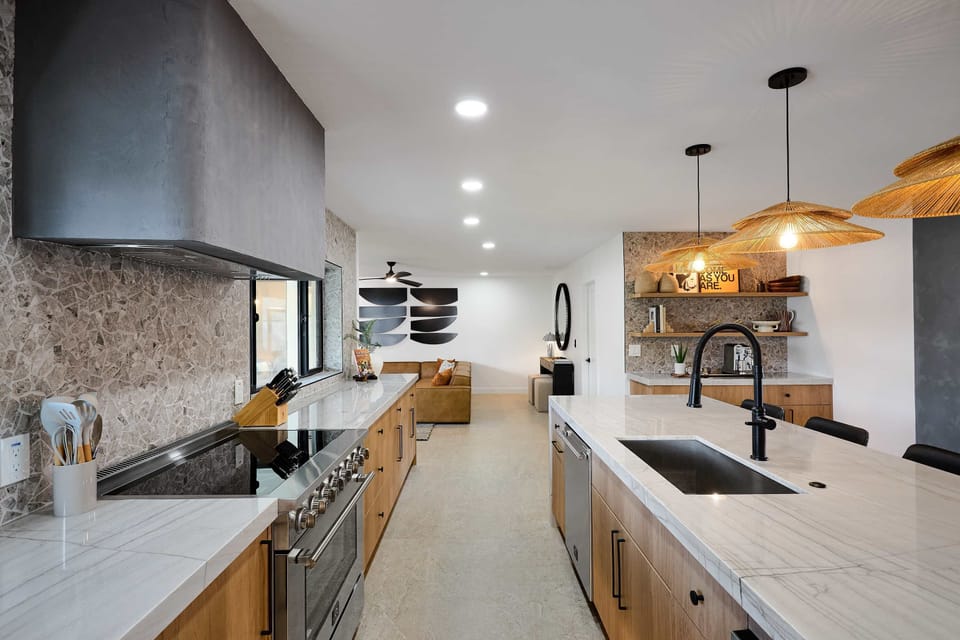 Sleek open concept kitchen with stainless steel appliances,  large island with breakfast bar seating for 5, coffee bar with espresso machine,  and fully equipped with your basic cooking essentials. 