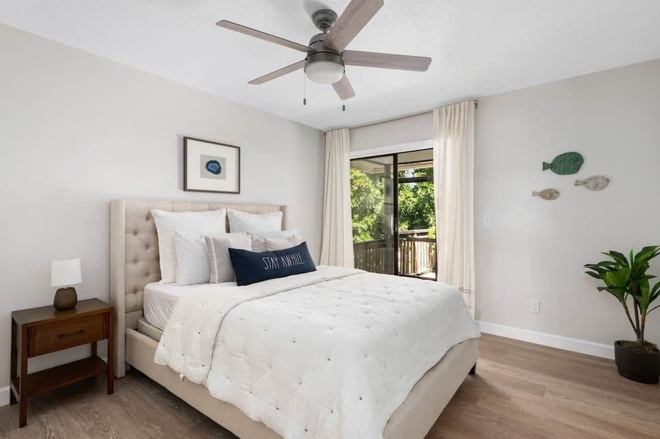 Guest bedroom opens to screened patio and outdoor deck with tropical view.