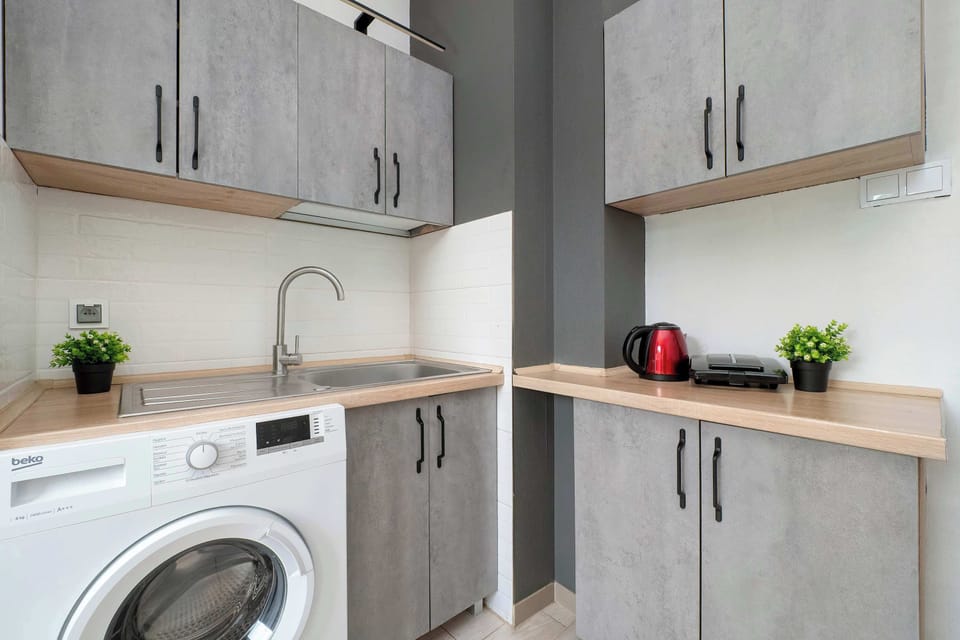 Kitchen with grey cabinets, a washing machine, and wooden countertops.