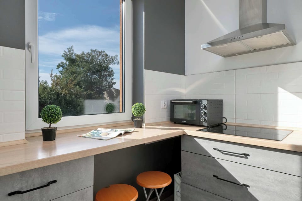 Well-equipped kitchen with white cabinets, wooden countertops, and a large window.