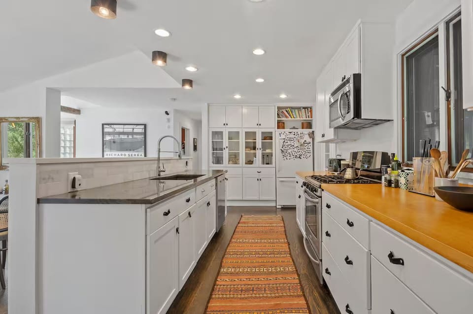Modern kitchen dishwasher, oven, stove, microwave, fridge, and cookware.