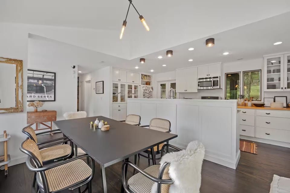 View of indoor dining and kitchen; French doors connecting to sunroom dining.