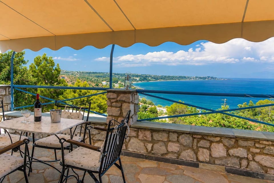 Covered terrace with outdoor dining and panoramic coastal views
