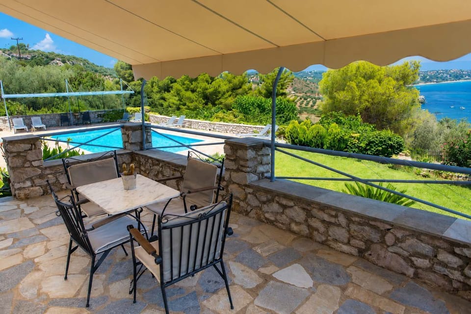 Private covered terrace with outdoor dining area and beautiful views across the gardens and sea.
