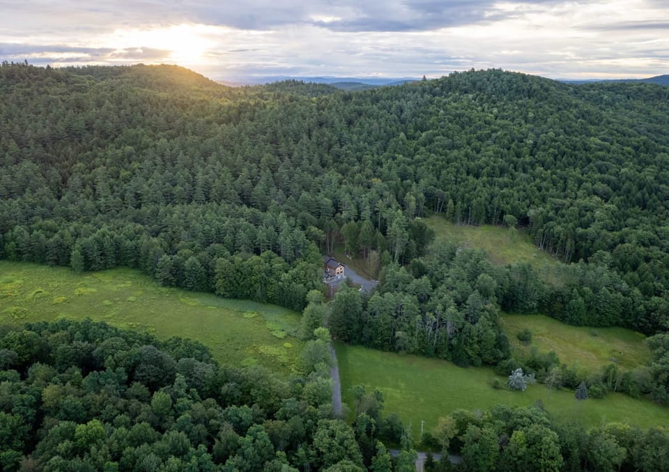 Escape into acres of untouched forest, with rolling hills and a golden sunset framing your private lodge in the distance.