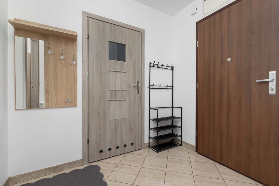 The entrance hallway features a brown front door, an interior room door, and a wall-mounted coat rack with a shoe organizer.