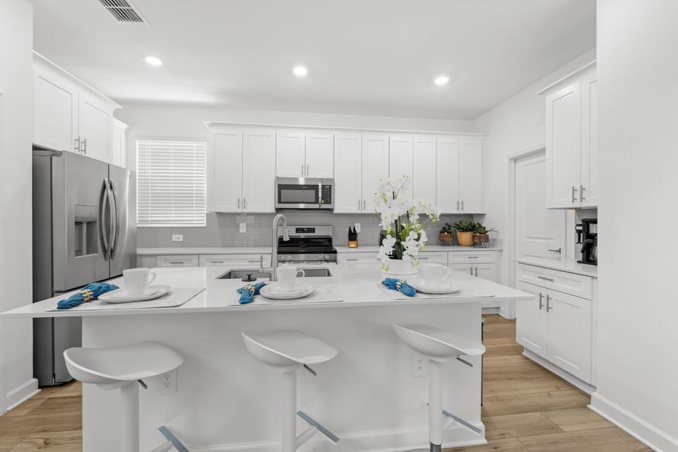 Gather around this bright, modern kitchen where crisp white cabinetry and sleek countertops invite you to whip up your favorite meals. Pull up a stool at the spacious island and enjoy your morning coffee in comfort.
