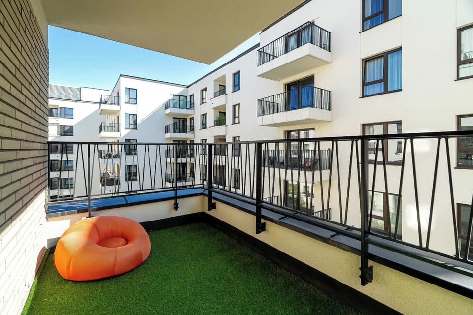 Spacious balcony covered in artificial grass and an orange chair.