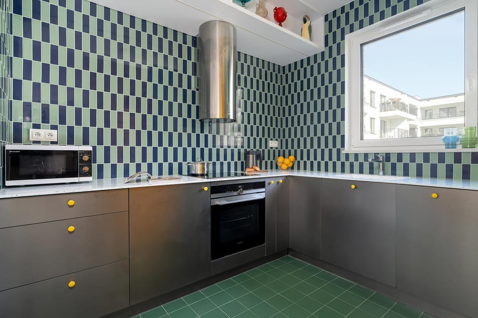Bright kitchenette combines colorful furniture, patterned walls, and large windows.