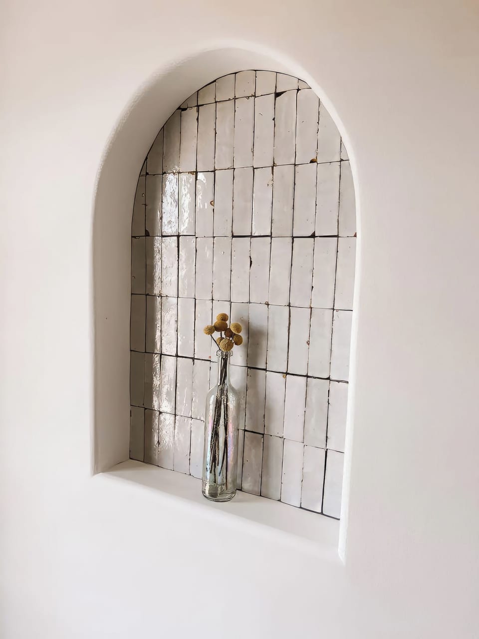 Pearly tile set into the arch, and a bottle of dried craspedia.