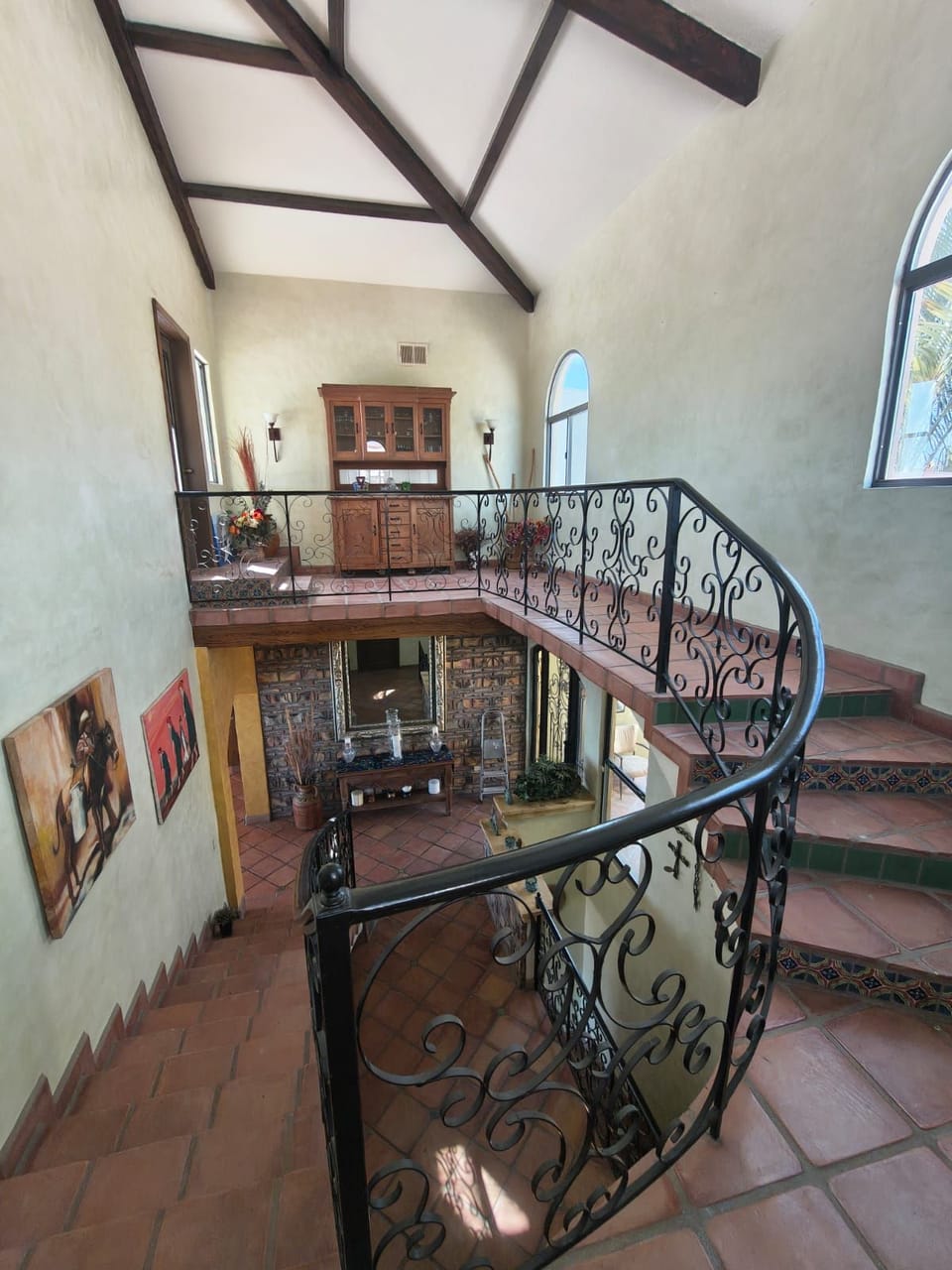 An eye-catching spiral staircase with decorative wrought iron railings and terracotta tile steps connecting the home's multiple levels.