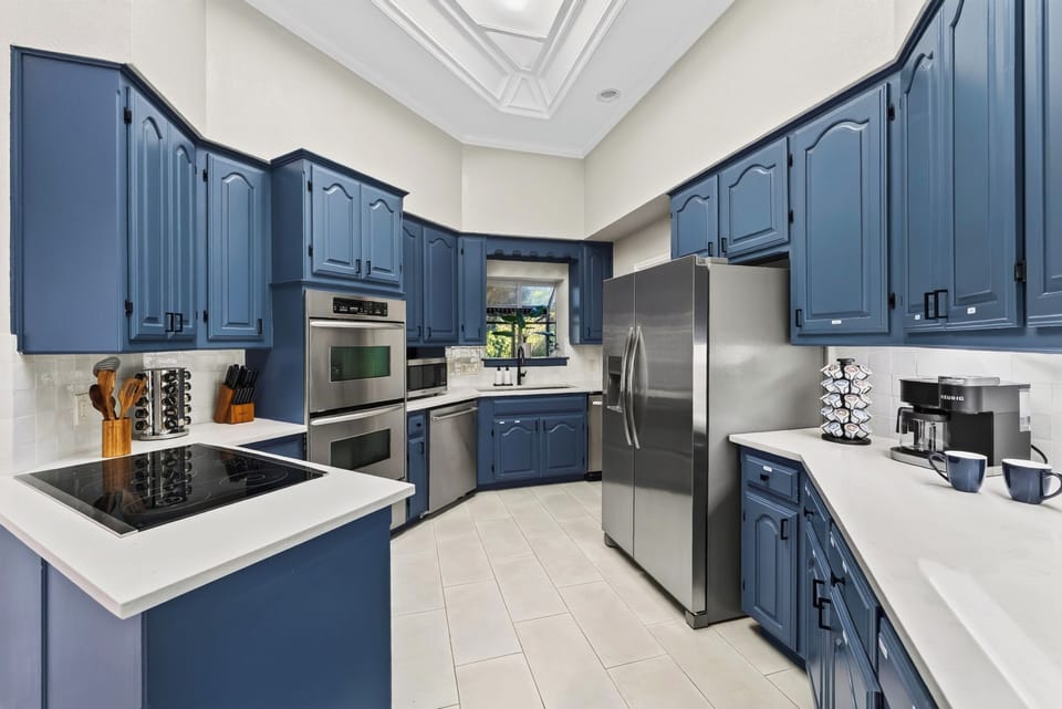 Fully equipped kitchen with blue cabinetry and stainless steel appliances.