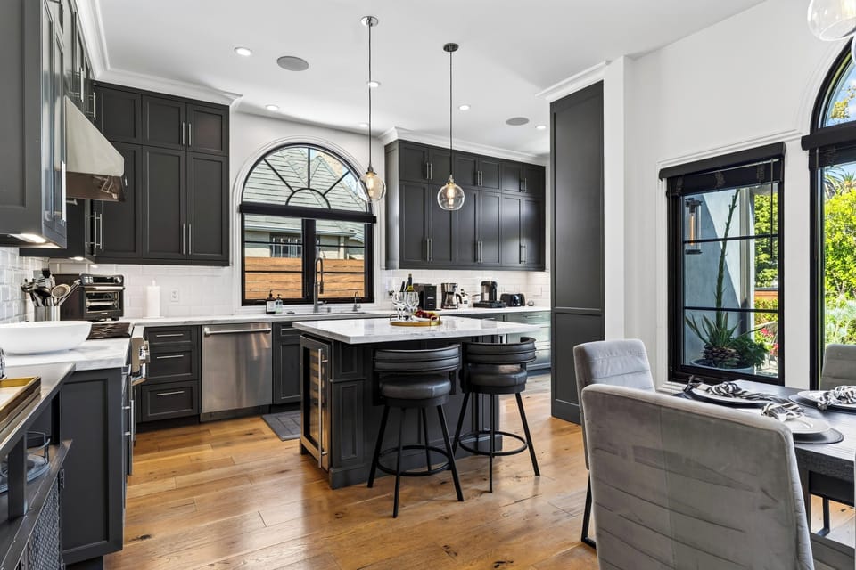 Chef's kitchen with a marble center island, pendant lights, and dark cabinetry.