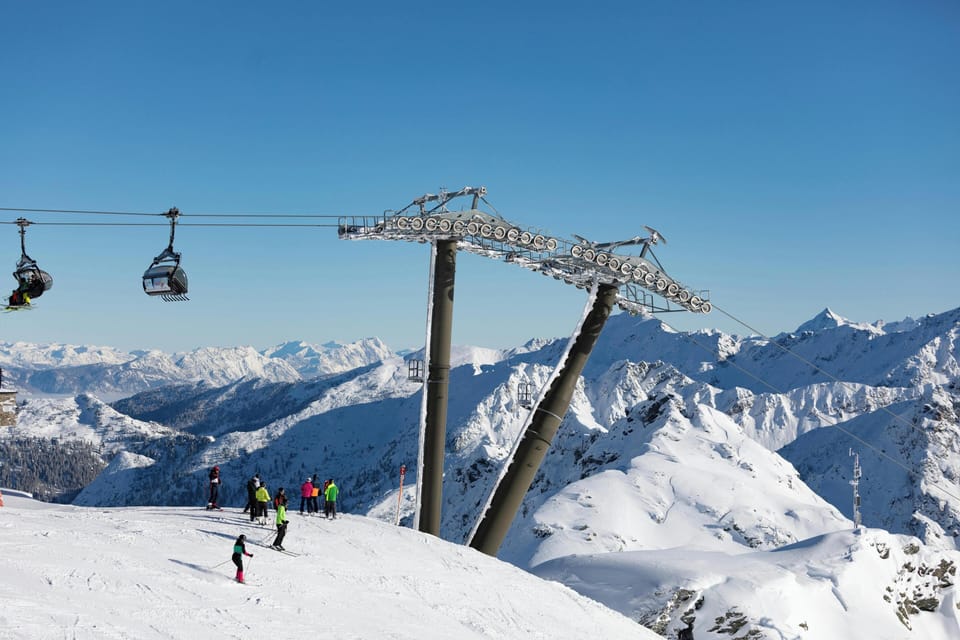 Gondola cable cars glide above skiers on the slopes with sweeping views of the French Alps